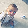 baby, child, sunglasses, white_shirt, beige_vest, blue_socks, white_sneaker, pacifier, rug, floor, indoor, cute, infant, fashion, accessory, playful, portrait, purple_heart, glasses, seated