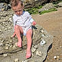 barefoot, beach, casual, child, clothing, coast, curly_hair, greenery, nature, outdoor, portrait, rock, sand, sea, shells, sunlight, sunny, toddler, trees, water