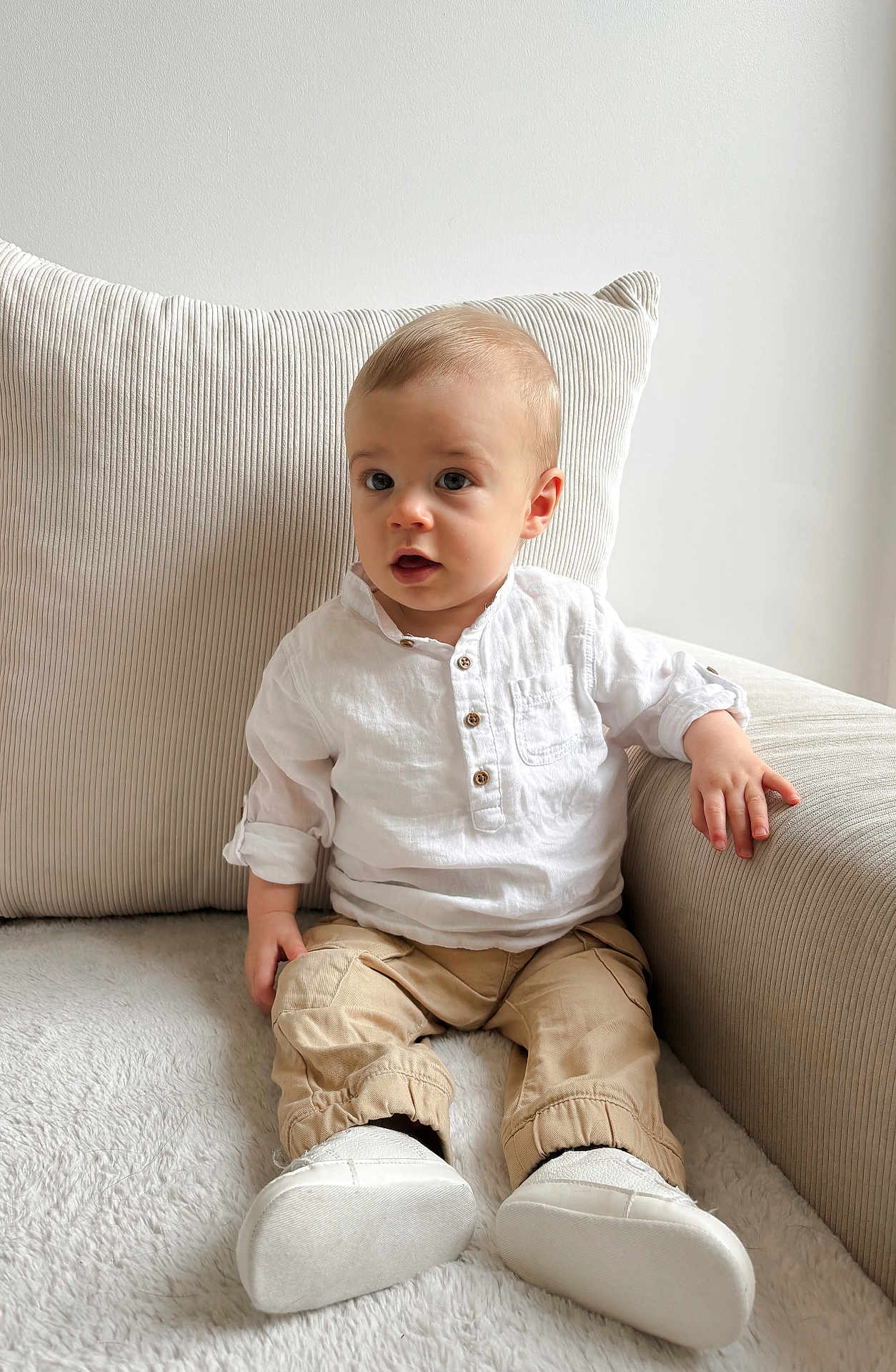 Noé a rejoint le concours — aidez-le/la à gagner de superbes lots ! baby, beige_pants, casual_clothing, child, comfortable, couch, cozy, curious_expression, furniture, home, indoor, person, pillow, portrait, sitting, soft_light, toddler, white_shirt, white_shoes, young_child