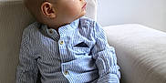 Noé participe au concours pour gagner de l'argent avec cette photo : armchair, baby, casual_clothing, child, cozy, curious, cute, expression, furniture, indoor, looking_away, pants, portrait, seated, side_profile, small_hands, socks, soft_lighting, striped_shirt, young_child