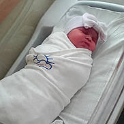 Skylar is registered to the contest to win money with this photo: newborn, baby, hospital, blanket, bassinet, bed, swaddled, hat, sleeping, infant, cute, white, resting, healthcare, child, person, indoors, soft, peaceful, portrait