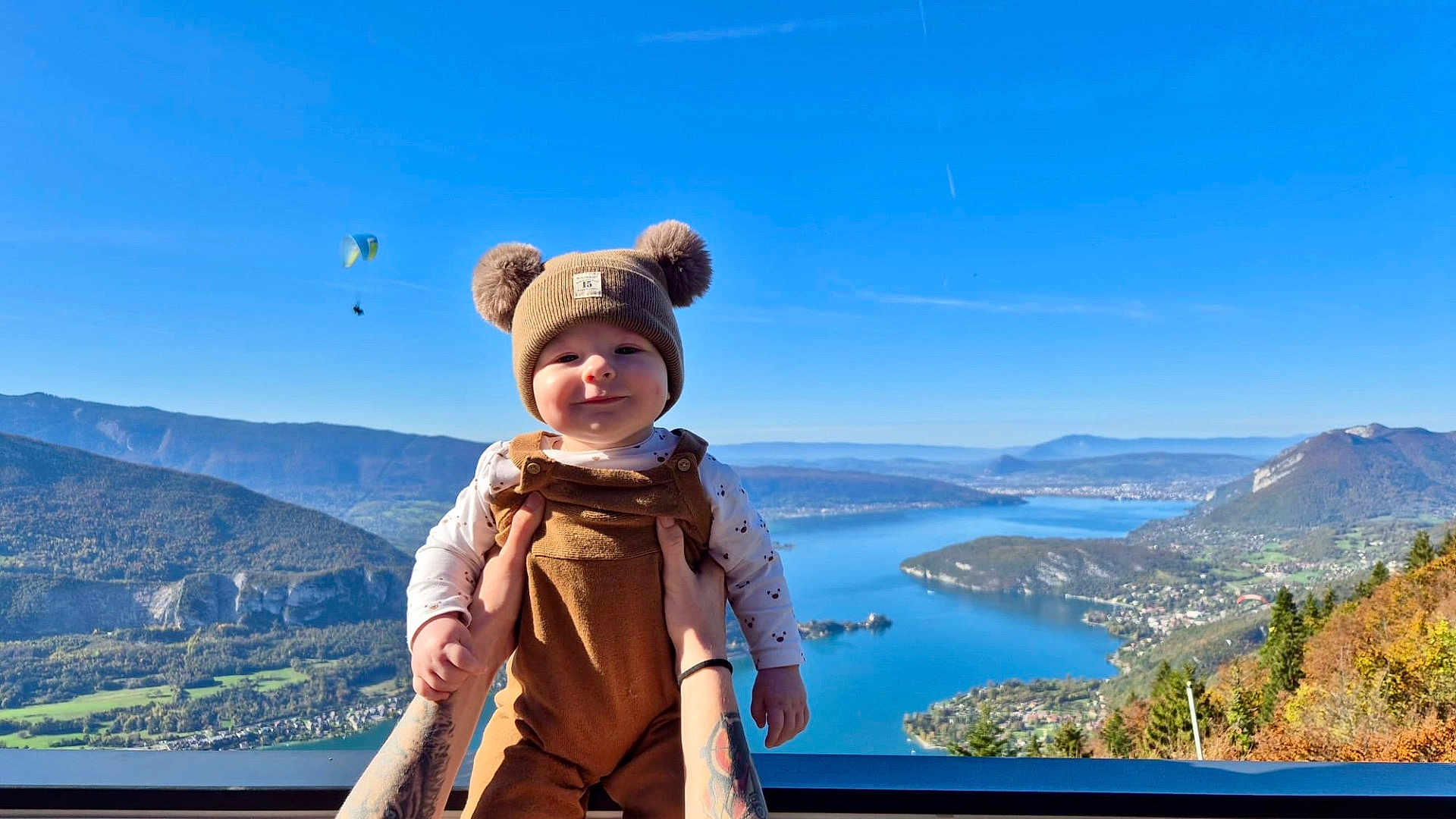 Valentin a rejoint le concours — aidez-le/la à gagner de superbes lots ! baby, child, person, hat, clothing, outdoor, sky, mountain, lake, water, nature, paraglider, hands, smile, scenery, blue_sky, forest, fall, sunny, portrait