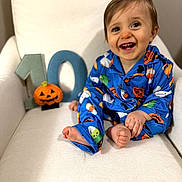 Wayne joined the competition — help win amazing prizes! baby, child, smiling, happy, portrait, halloween, pumpkin, pajamas, blue_clothing, chair, sitting, indoors, white_background, number_ten, jack_o_lantern, infant, barefoot, playful, photography, face
