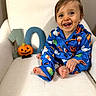 baby, child, smiling, happy, portrait, halloween, pumpkin, pajamas, blue_clothing, chair, sitting, indoors, white_background, number_ten, jack_o_lantern, infant, barefoot, playful, photography, face