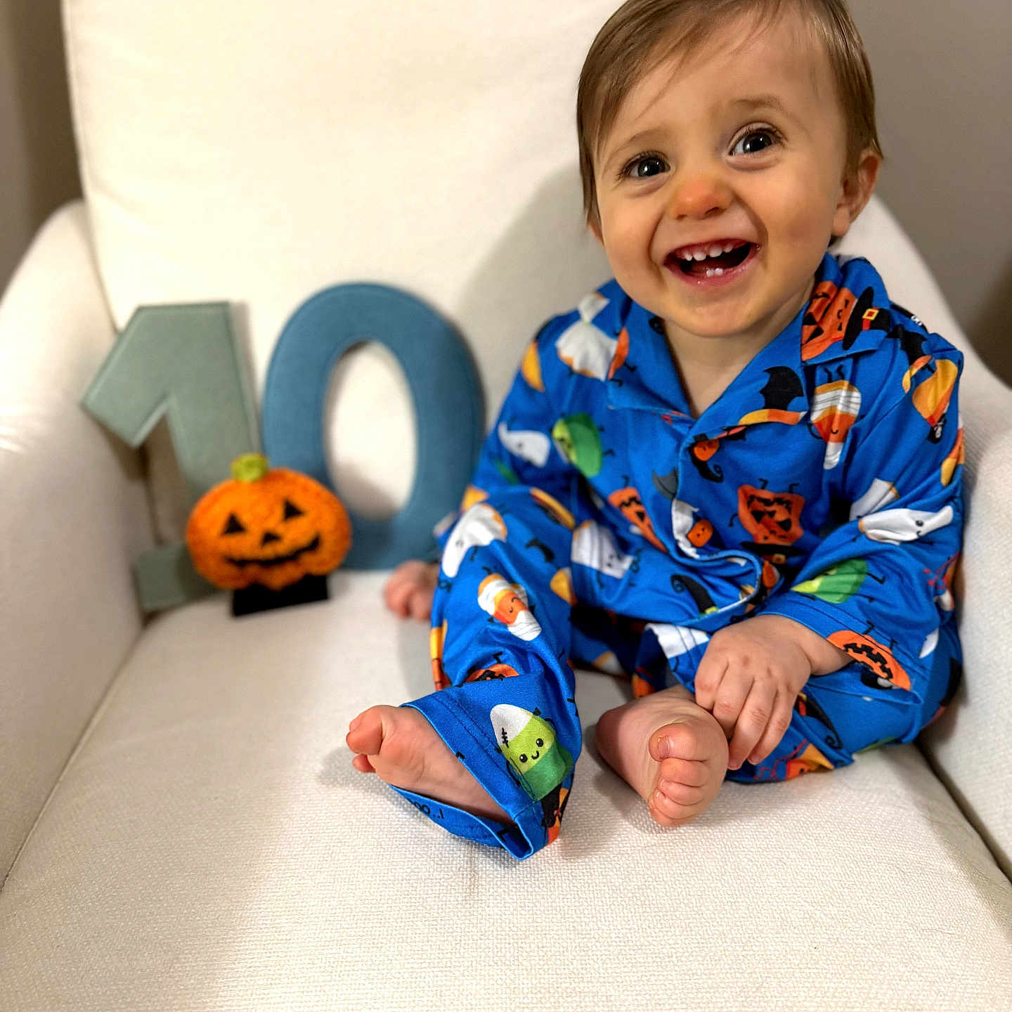 Wayne joined the competition — help win amazing prizes! baby, child, smiling, happy, portrait, halloween, pumpkin, pajamas, blue_clothing, chair, sitting, indoors, white_background, number_ten, jack_o_lantern, infant, barefoot, playful, photography, face