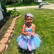 Nova is registered to the contest to win money with this photo: child, girl, smiling, tutu_dress, purple, blue, beaded_hair, outdoor, grass, sunny, accessories, bracelet, headband, happy, flower, shoes, lawn, house, daylight, portrait