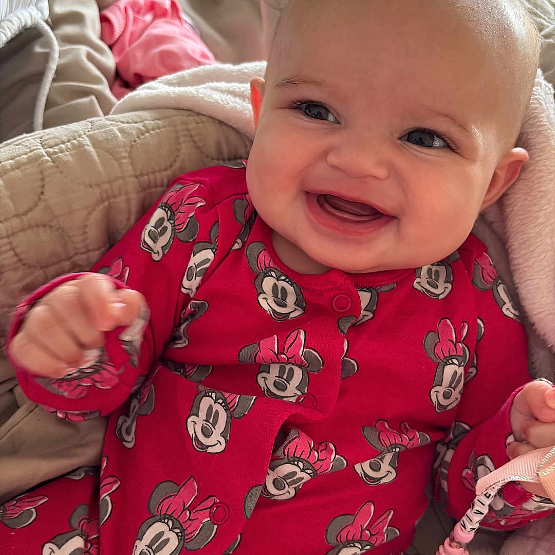 Vivienne joined the competition — help win amazing prizes! baby, blanket, child, comfort, cozy, cute, face, hand, happy, head, indoor, infant, minnie_mouse, onesie, person, portrait, red_clothing, small_toy, smiling, soft_texture