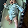 baby, infant, onesie, bathtub, bath, child, smiling, tongue_out, happy, skin, legs, arm, wooden_floor, baby_bath, buttoned_clothing, person, indoor, cute, playful, newborn
