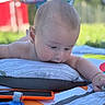 Rhett joined the competition — help win amazing prizes! baby, child, pillow, play_mat, toy, outdoor, grass, curious, infant, close_up, head, face, arm, colorful, sunlight, nature, blurred_background, soft_texture, skin, exploring