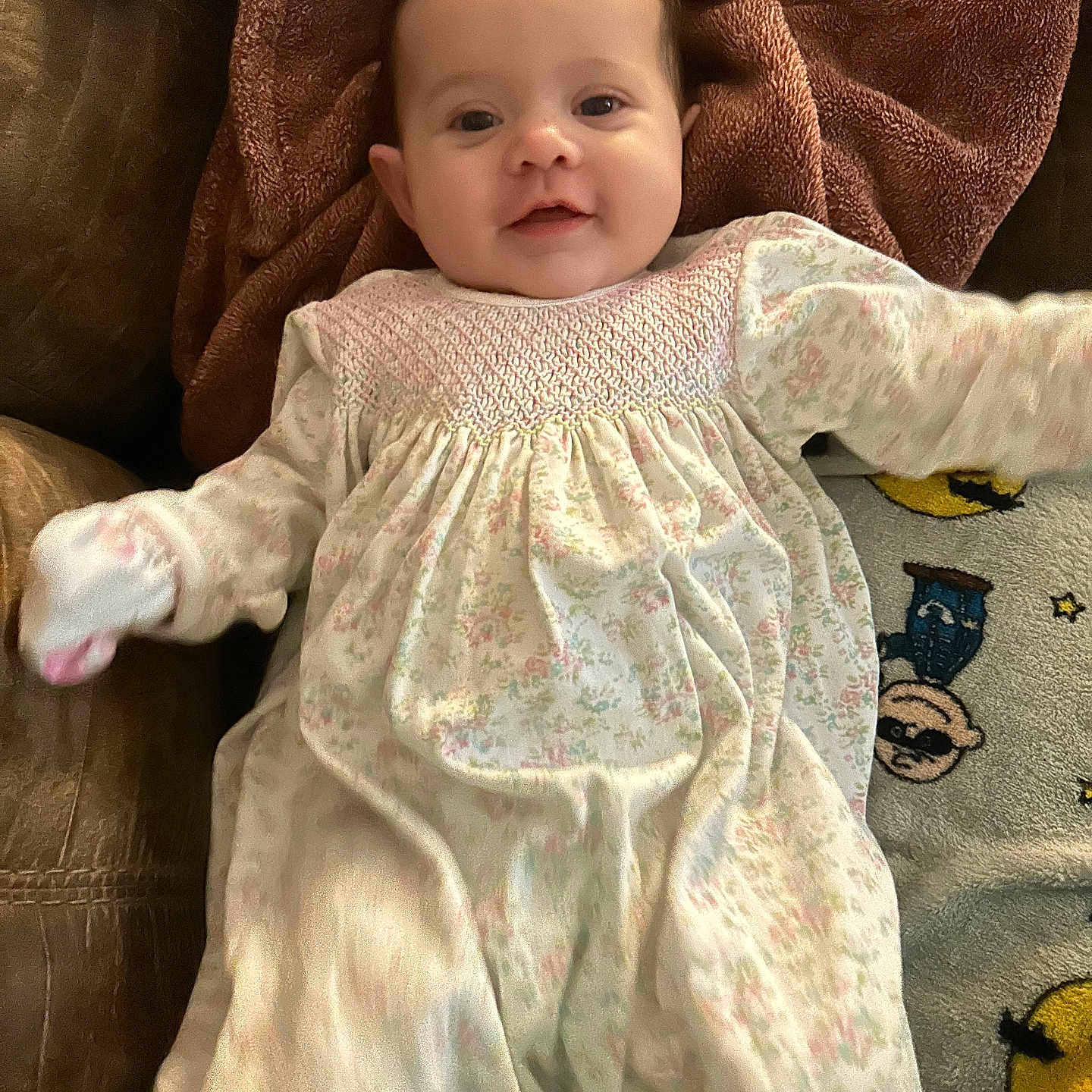 Lilly joined the competition — help win amazing prizes! baby, child, smiling, floral_dress, blanket, rug, indoor, cute, happy, person, infant, lying_down, cozy, soft_texture, portrait, young_child, home, warm_colors, playful, fun