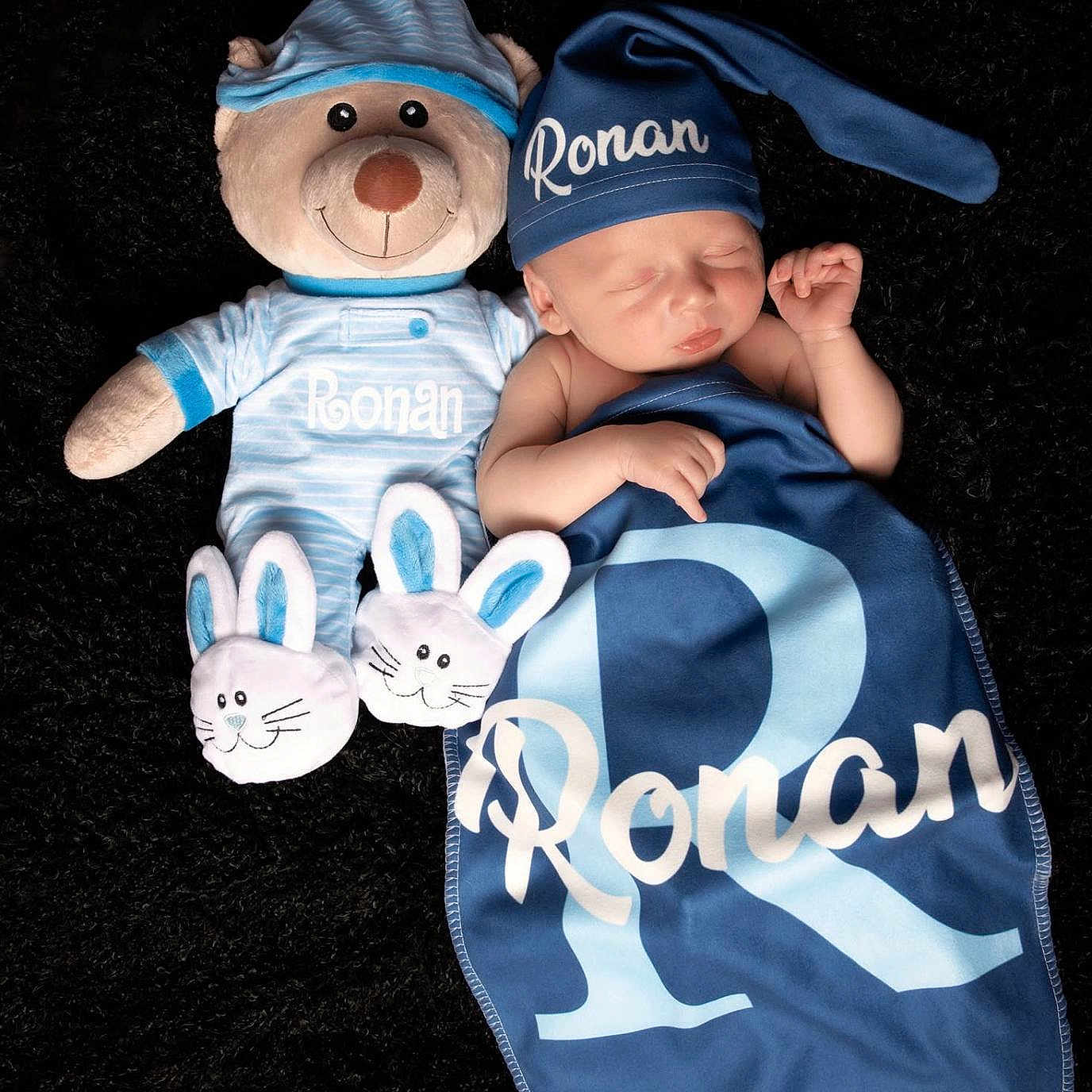 Ronan is registered to the contest to win money with this photo: baby, newborn, sleeping, teddy_bear, blue_blanket, blue_hat, soft_toy, personalized, name, pajamas, cute, infant, resting, cozy, black_background, child, comfort, peaceful, portrait, sleep