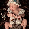 baby, infant, sleeping, knit_hat, knit_vest, fishing_pole, fish, plush_background, cute, handmade, cozy, newborn, child, sleep, soft_texture, wooden_stick, tiny_fish, relaxation, portrait, adorable