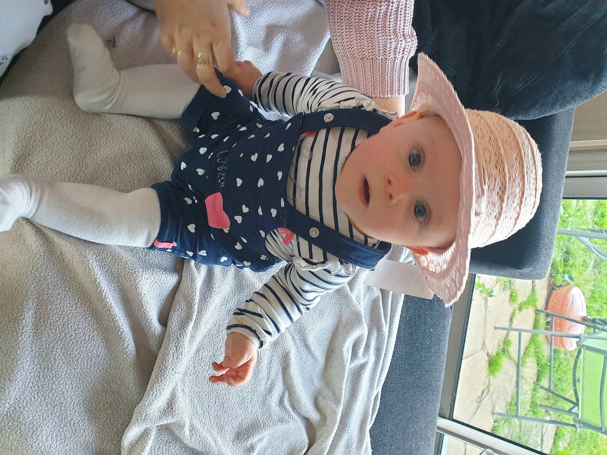 Lila a rejoint le concours — aidez-le/la à gagner de superbes lots ! baby, baby_toddler_clothing, child, comfort, finger, grass, hand, happy, hat, headwear, human_leg, lap, pattern, person, plant, sleeve, sun_hat, surprise, textile, thigh