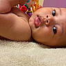 Ryan is registered to the contest to win money with this photo: baby, infant, face, tongue, blanket, soft, cute, lying_down, curious, skin, arm, child, indoors, toy, colorful, expression, portrait, young, head, sleepwear