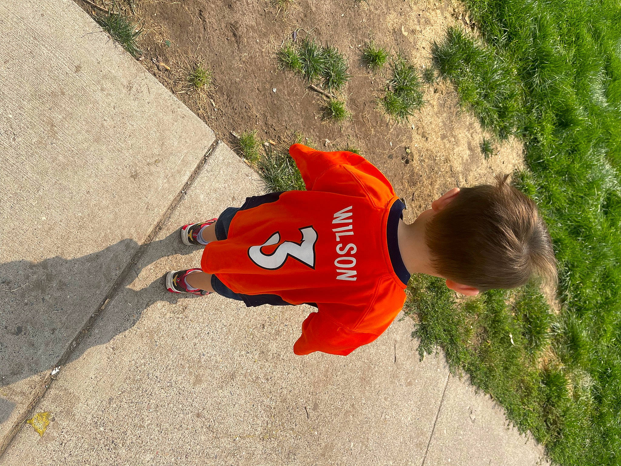 Owyn is registered to the contest to win money with this photo: asphalt, carmine, concrete, flooring, font, grass, hat, landscape, people_in_nature, person, plant, play, recreation, road_surface, shadow, sidewalk, soil, tail, toddler, tree
