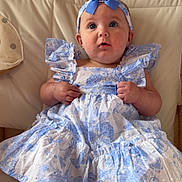 Eleanor joined the competition — help win amazing prizes! baby, child, blue_bow, dress, headband, sitting, couch, curious, indoors, foot, cute, portrait, person, furniture, fabric, pattern, smiling, happy, skin, young