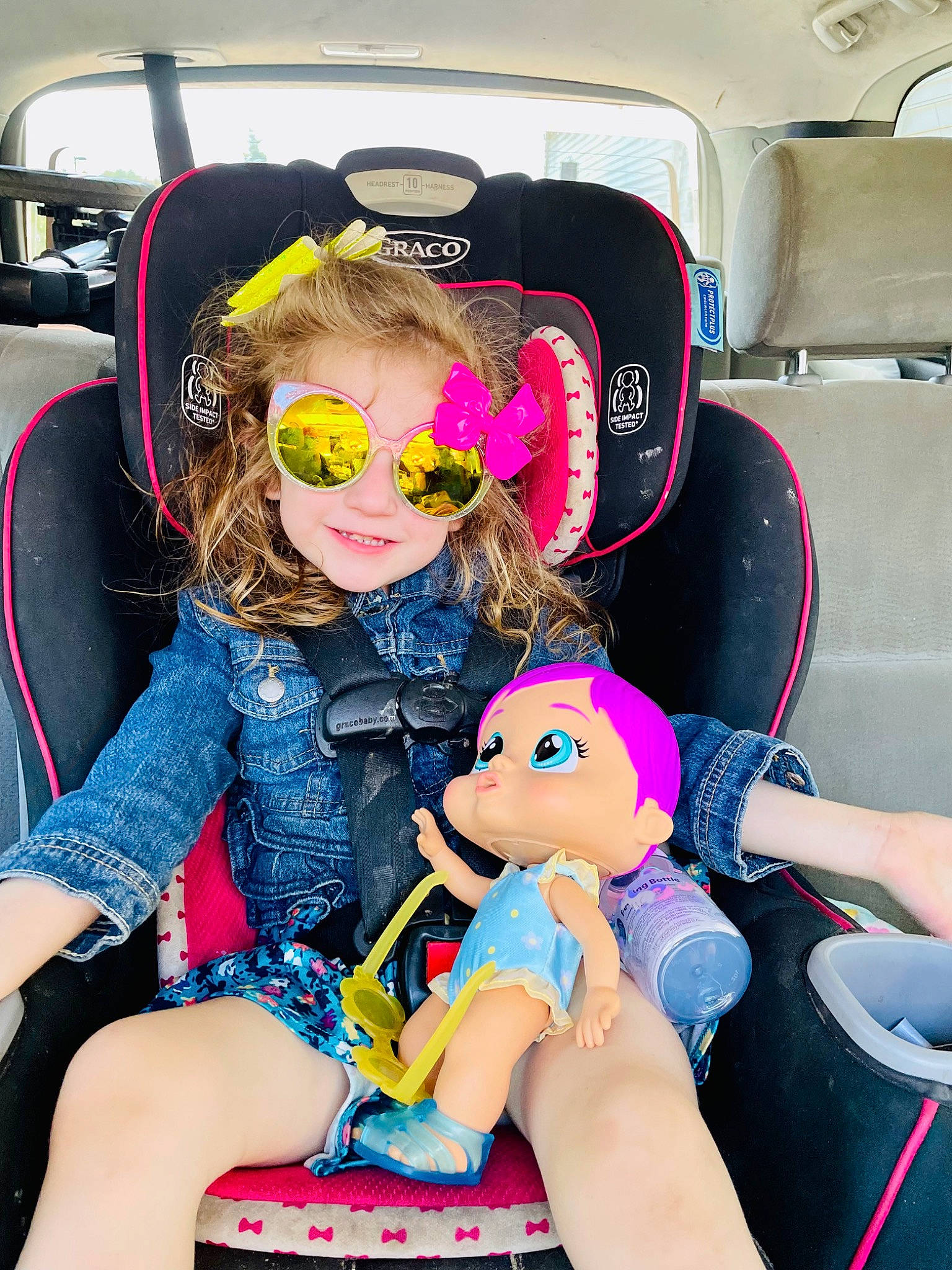 Ellianna is registered to the contest to win money with this photo: auto_part, automotive_design, automotive_exterior, car_seat, car_seat_cover, child, event, eyewear, fun, hairstyle, human_leg, joy, lap, leisure, motor_vehicle, person, personal_protective_equipment, pink, steering_wheel, thigh