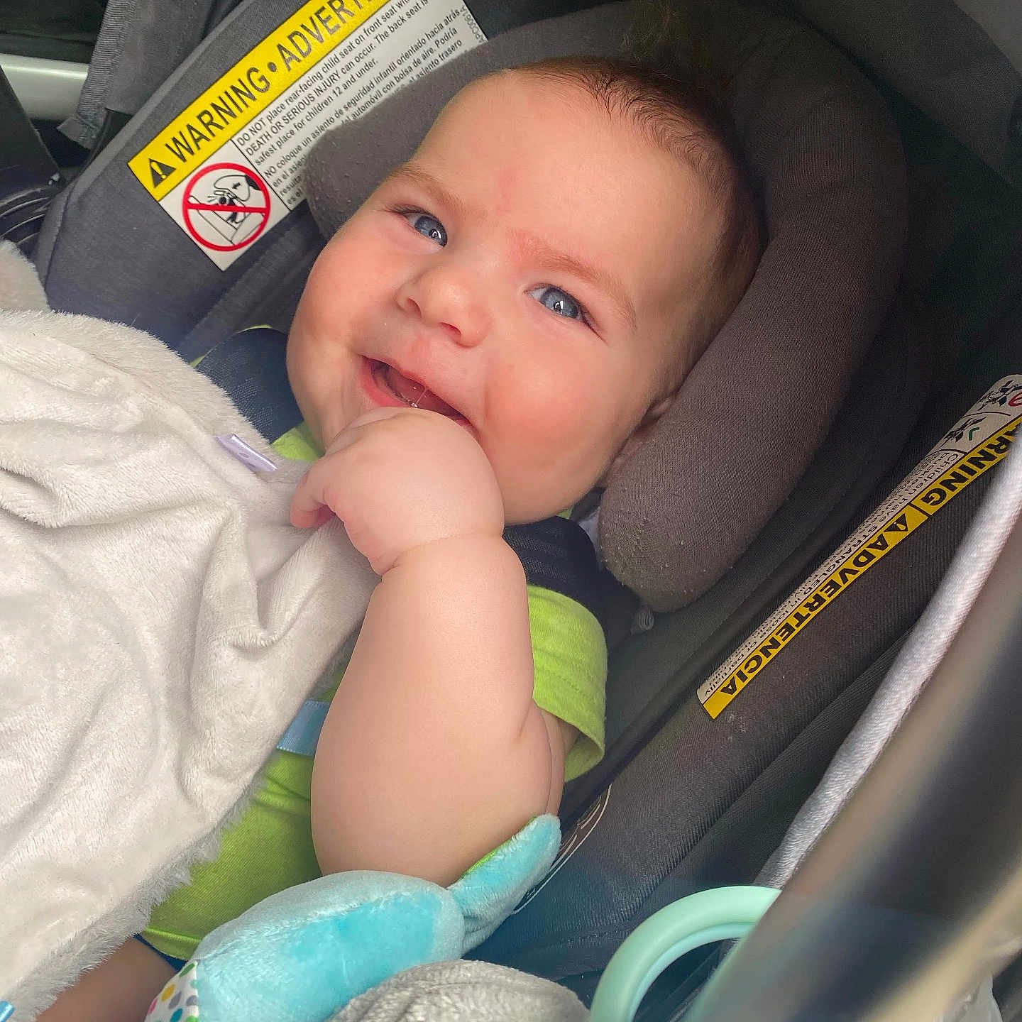 Ollie is registered to the contest to win money with this photo: baby, blanket, blue_eyes, buckle, car_seat, chubby_cheeks, closeup, clothing, hand, happy, headrest, infant, infant_toy, plush_toy, portrait, seatbelt, smiling, stroller, toy_ring, warning_label