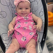 Aria joined the competition — help win amazing prizes! baby, infant, smile, pink_clothing, headband, romper, baby_rocker, seat, child, cute, happy, tongue_out, indoor, person, young_child, face, legs, hands, playful, comfort