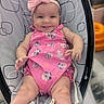 baby, infant, smile, pink_clothing, headband, romper, baby_rocker, seat, child, cute, happy, tongue_out, indoor, person, young_child, face, legs, hands, playful, comfort