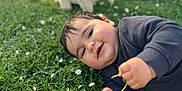 Yanis participe au concours pour gagner de l'argent avec cette photo : baby, child, grass, flower, daisy, plush_toy, dog_toy, outdoor, nature, smiling, happy, cute, laying_down, sunlight, greenery, playing, young_child, casual_clothing, daytime, relaxing