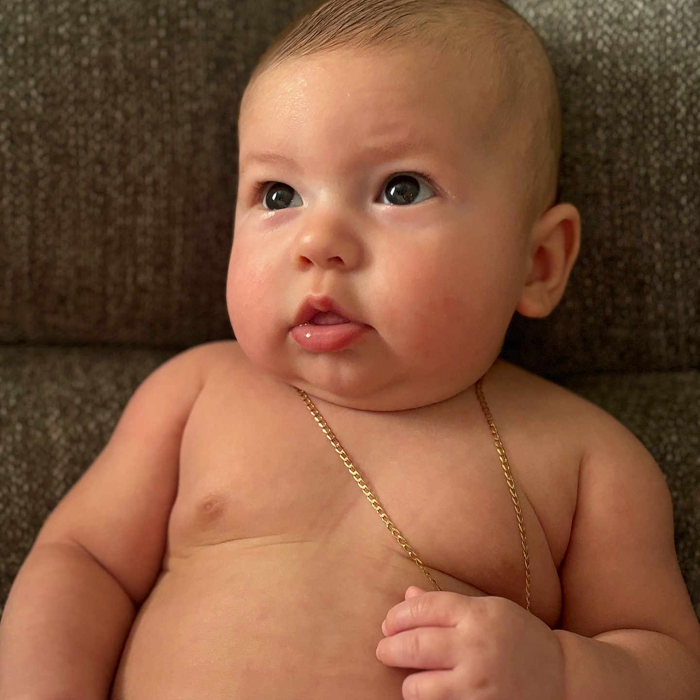 Angelo is registered to the contest to win money with this photo: accessories, baby, bodypart, couch, face, finger, furniture, hand, hardwood, head, jewelry, necklace, newborn, person, photography, portrait, sitting, strap, toe, wood