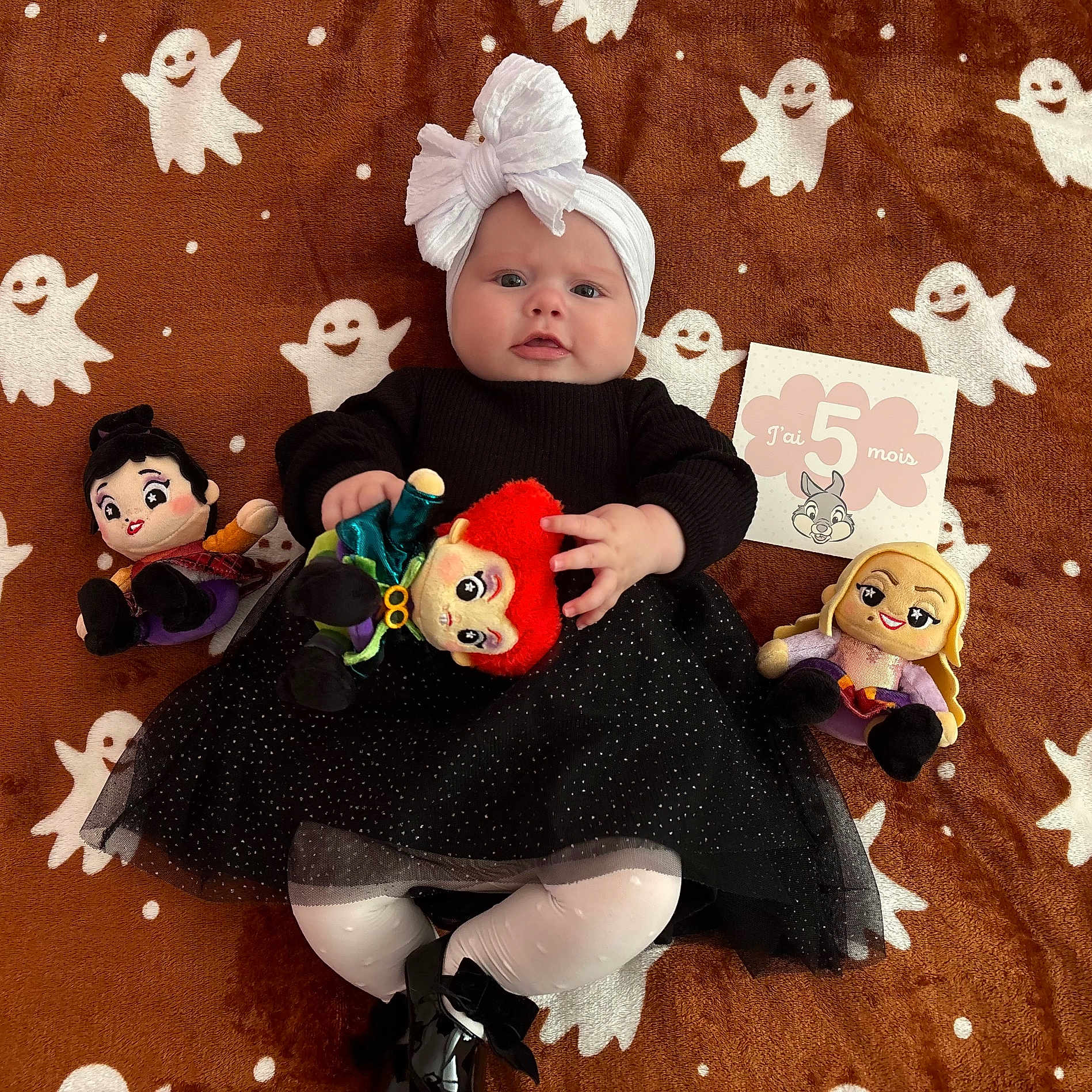 Rowena participe au concours pour gagner de l'argent avec cette photo : baby, black_dress, black_shoes, blanket, child, cute, five_months, ghost_pattern, happy, headband, indoor, infant, lying_down, milestone_card, plush_doll, portrait, smiling, toy, white_bow, white_tights