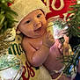 baby, santa_hat, christmas, holiday, ornament, glowing_light, smile, happy, festive, decorations, infant, cute, celebration, christmas_tree, holiday_spirit, red, green, joyful, portrait, indoors
