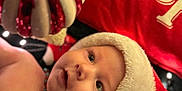 Livaï participe au concours pour gagner de l'argent avec cette photo : baby, background, cheeks, christmas, closeup, curious, cute, decoration, face, festive, green, holiday, infant, ornament, red, santa_hat, seasonal, soft_lighting, warm, white