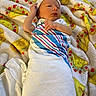 Atlas is registered to the contest to win money with this photo: baby, newborn, infant, child, sleeping, lying_down, blanket, swaddled, hat, striped_clothing, face, portrait, indoors, bed, textile, colorful, cozy, hands, photography, relaxed