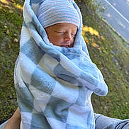 Atlas joined the competition — help win amazing prizes! newborn, baby, sleeping, infant, portrait, blanket, swaddled, hat, striped_hat, blue, outdoor, held, peaceful, face, closed_eyes, road, trees, grass, daylight, cozy