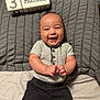 baby, infant, smiling, clapping, milestone_blocks, 3_months, gray_pillow, bed, lying_down, short_sleeve_shirt, black_pants, happy, cute, portrait, child, young_baby, indoors, human, person, cheerful