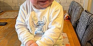 William joined the competition — help win amazing prizes! toddler, child, smiling, pajamas, table, fork, food, plate, fries, indoors, kitchen, wooden_table, happy, cute, clothing, person, face, sitting, home, playful