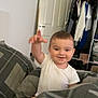 William joined the competition — help win amazing prizes! toddler, child, bed, blanket, plaid, smile, happy, indoor, clothing, wardrobe, door, person, furniture, room, hand, white_shirt, hair, face, reaching, cozy