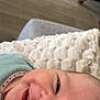 baby, smile, face, closeup, blanket, texture, indoor, floor, wooden_floor, furniture, chair, happy, infant, person, head, cozy, candid, skin, baby_clothing, expression