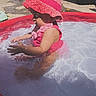 Jennifer is registered to the contest to win money with this photo: toddler, child, pool, water, pink, swimsuit, hat, sunhat, outdoor, summer, splashing, backyard, fence, playing, baby, sunlight, happy, sitting, water_play, daytime