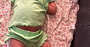 Jennifer is registered to the contest to win money with this photo: baby, infant, green_clothing, blanket, floral_pattern, lying_down, indoors, soft_fabric, cute, child, newborn, relaxed, skin, legs, arms, head, face, expression, comfort, resting