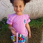 Felicia participe au concours pour gagner de l'argent avec cette photo : candy, cartoon_character, casual_clothing, child, chocolate, cute, daylight, easter_basket, footwear, grass, greenery, happy, holding, outdoor, person, pink_shirt, smile, standing, wall, young