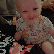 Alice is registered to the contest to win money with this photo: baby, child, smiling, portrait, indoor, person, clothing, floral_pattern, cute, happy, blue_eyes, sitting, short_hair, infant, colorful_shirt, cartoon_character, hand, cozy, casual, home
