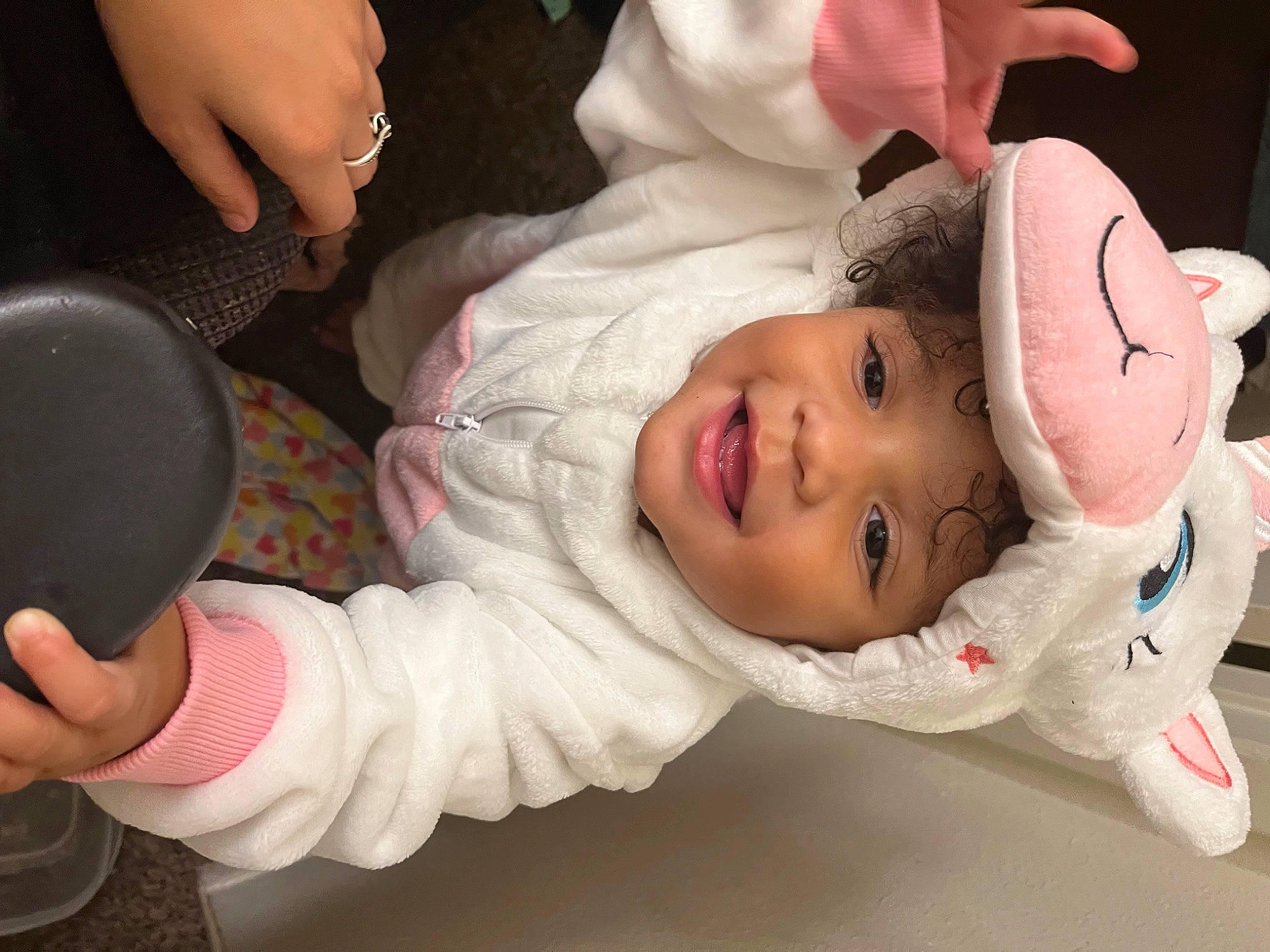 Arianna is registered to the contest to win money with this photo: baby, baby_toddler_clothing, cheek, child, eye, eyelash, facial_expression, finger, happy, head, headgear, headwear, human_body, lip, mouth, nose, person, pink, skin, sleeve