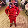 Janyla joined the competition — help win amazing prizes! child, red_clothing, heart_sunglasses, braided_hair, beads, indoor, carpet, shoes, patterned_shoes, standing, hands_on_hips, playful, colorful, person, young_child, room, chair, table, messy_room, casual