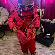 Janyla is registered to the contest to win money with this photo: child, toddler, sunglasses, heart_shaped, pink_jacket, red_pants, colorful_beads, braided_hair, indoor, carpet, chair, curtains, shoes, shoe_box, radiator, floor, fashion, cool, cute, person