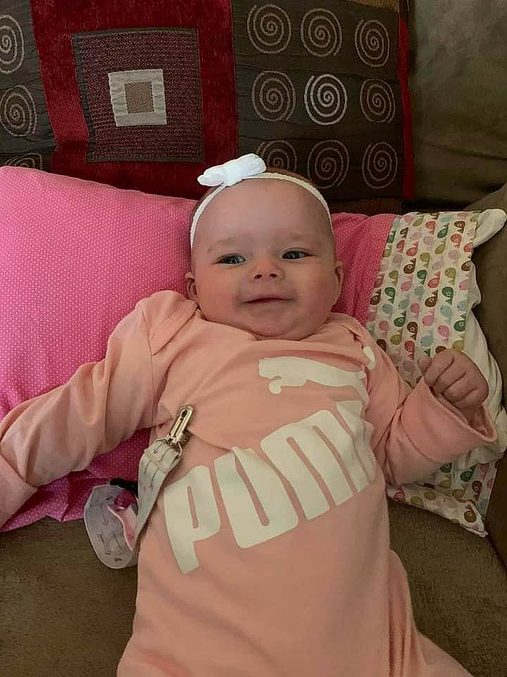Karley is registered to the contest to win money with this photo: baby, baby_safety, baby_toddler_clothing, cap, cheek, child, comfort, couch, face, happy, linens, person, pillow, pink, room, sleeve, smile, t_shirt, textile, throw_pillow