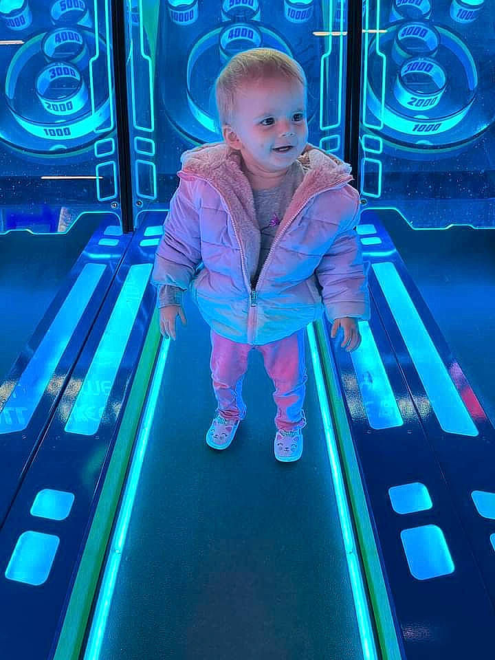 Karley is registered to the contest to win money with this photo: baby, blue, child, city, electric_blue, entertainment, fun, leisure, light, magenta, neon, person, photograph, playground, purple, recreation, snapshot, sneakers, standing, technology