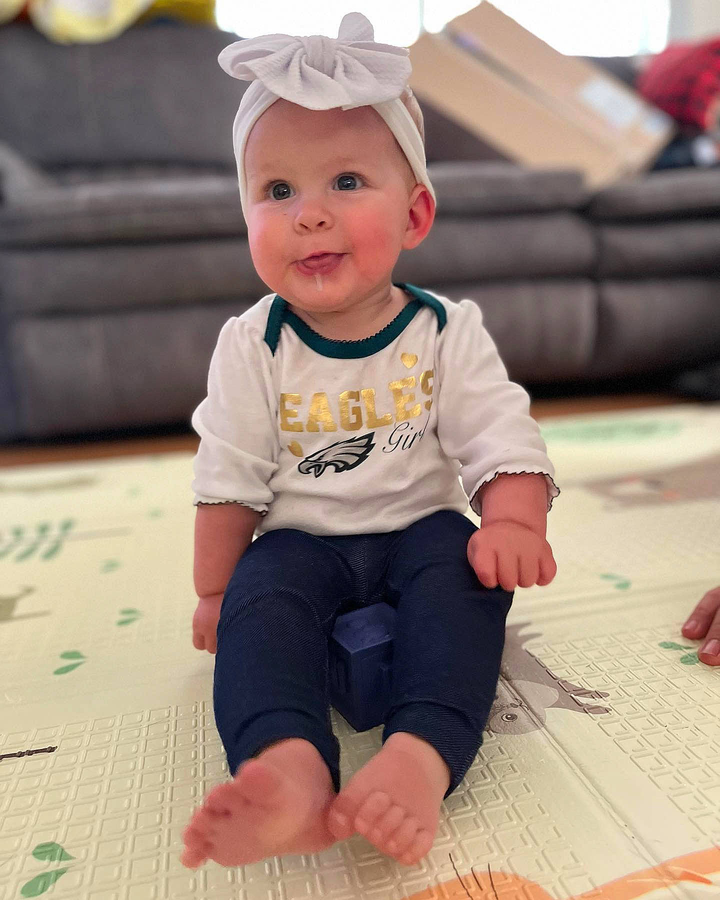 Blakelyn is registered to the contest to win money with this photo: baby, baby_toddler_clothing, barefoot, cap, child, clothing, costume_hat, couch, flooring, fun, happy, hat, headwear, pattern, person, sitting, skin, sleeve, smile, t_shirt