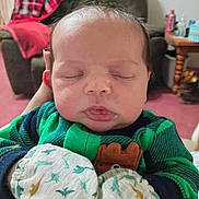 Oliver joined the competition — help win amazing prizes! baby, sleeping, infant, mittens, clothing, green, dinosaur_pattern, face, person, indoor, furniture, blanket, couch, table, hand, head, peaceful, young_child, cozy, portrait