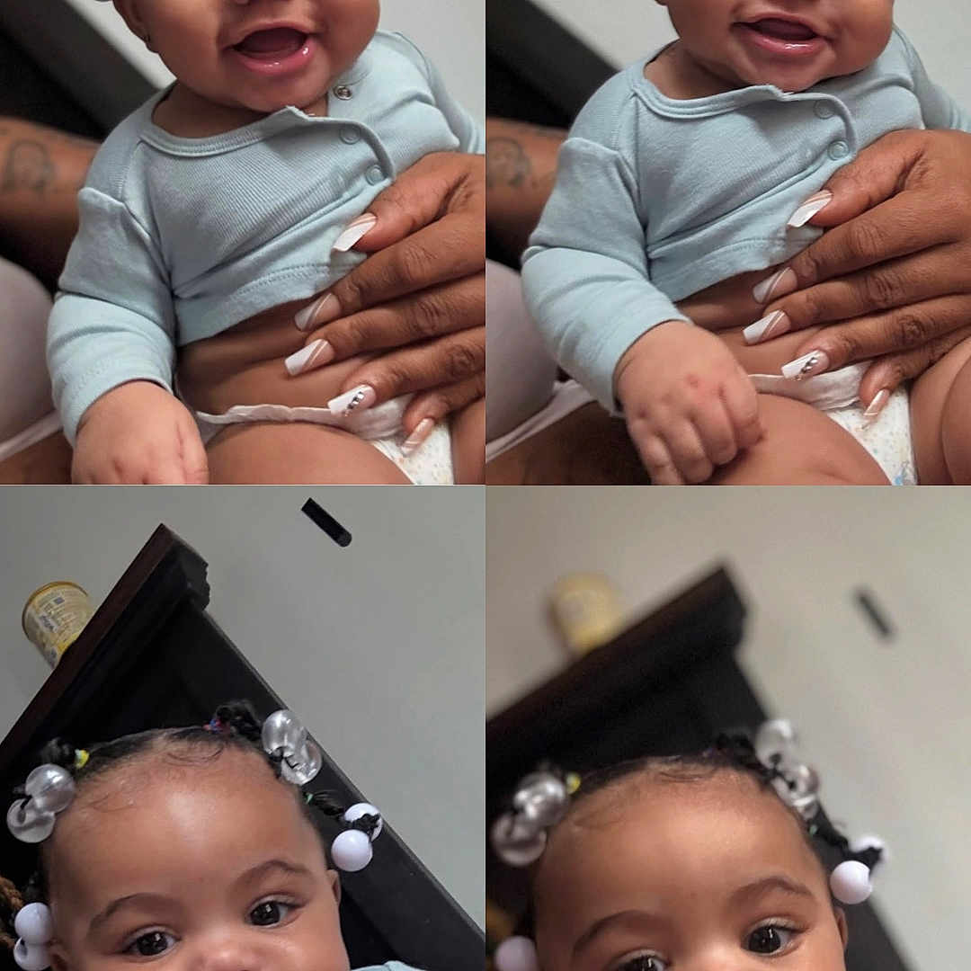 Germany is registered to the contest to win money with this photo: baby, child, smiling, cute, portrait, close_up, infant, hair_accessories, blue_clothing, hand, manicured_nails, indoor, person, expression, holding, adorable, skin, face, young_child, happy