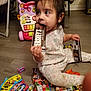 toddler, child, chocolate, hersheys, candy, floor, pajamas, toy, stroller, indoor, playtime, snack, sweet, colorful, messy, hand, face, sitting, curious, young_child
