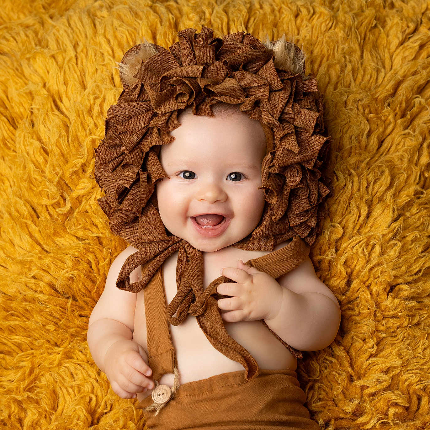 Côme participe au concours pour gagner de l'argent avec cette photo : baby, bonnet, brown, child, closeup, clothing, costume, cute, ears, fabric, face, hands, happy, infant, lion, lying_down, portrait, smile, soft_texture, yellow