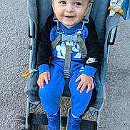 Elijah participe au concours pour gagner de l'argent avec cette photo : baby, child, stroller, smile, blue_clothing, nike, shoes, outdoor, pavement, seatbelt, happy, person, casual, cute, toddler, footwear, jumpsuit, toy, hand, face